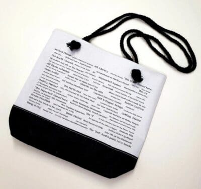 A white bag with black strap and words on it.