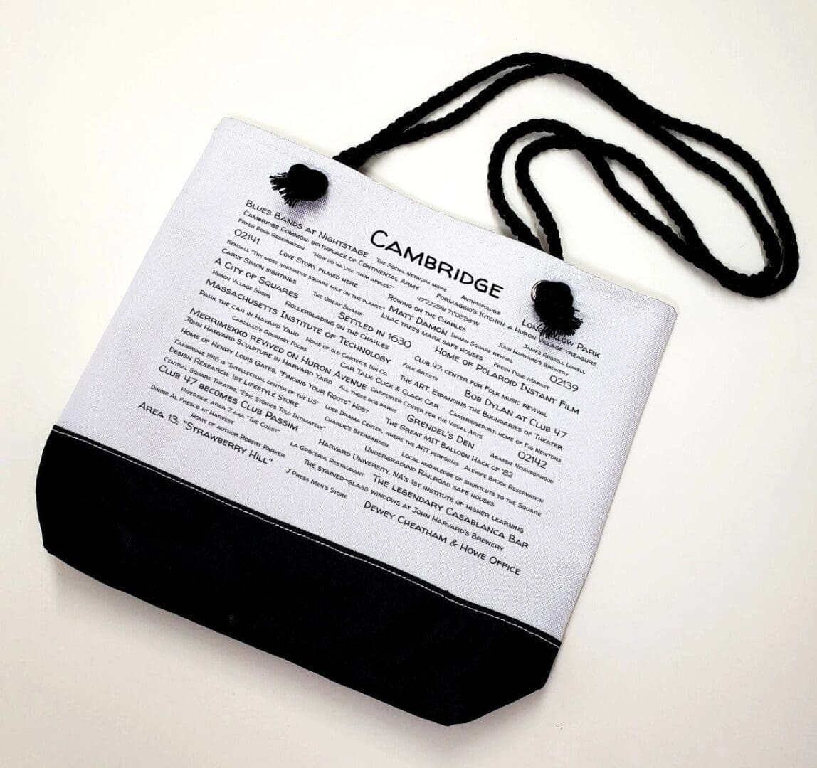 A white bag with black strap and words on it.