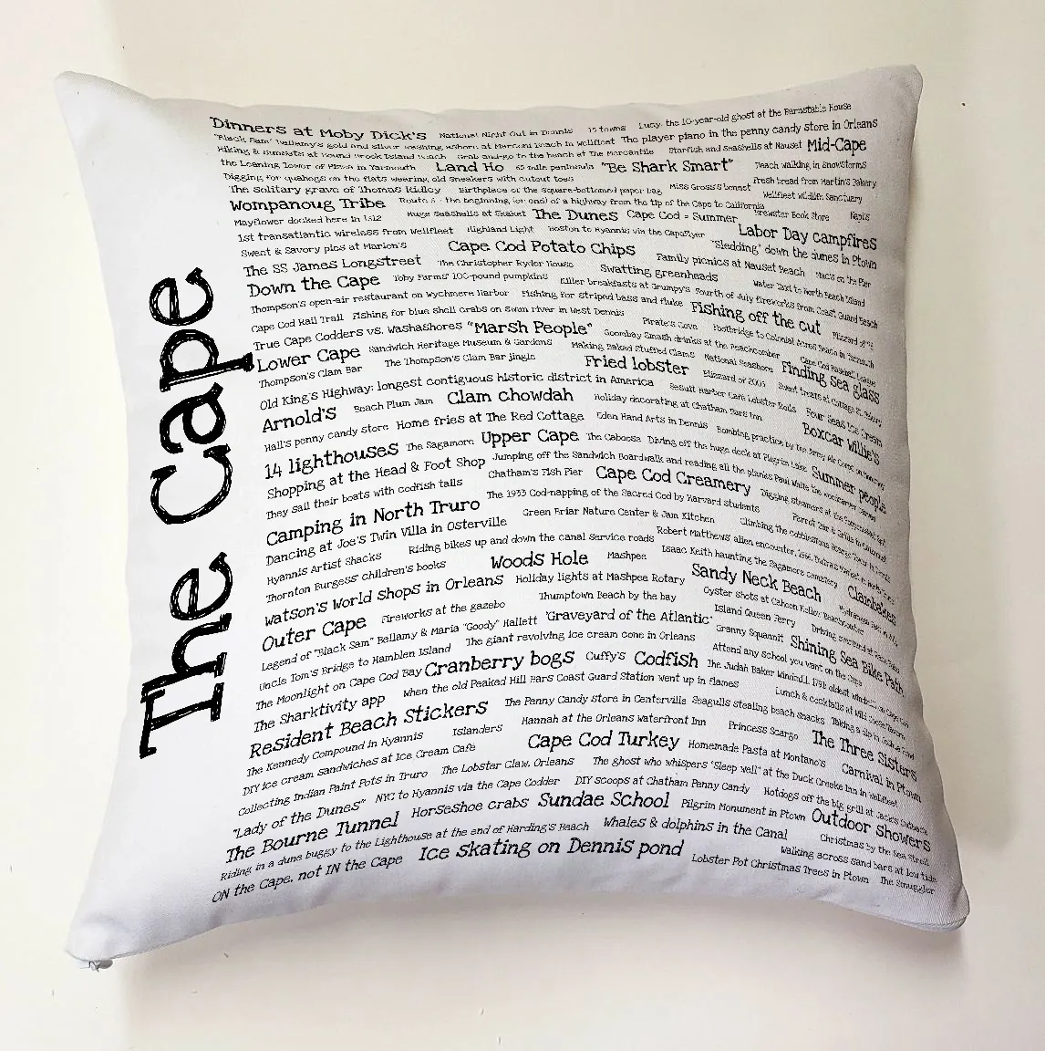 A white pillow with the word " cape " written on it.