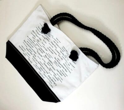 A white bag with black handles and writing on it.