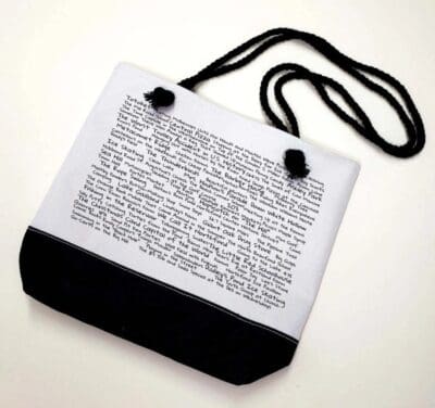 A white bag with black handles and a text on it.