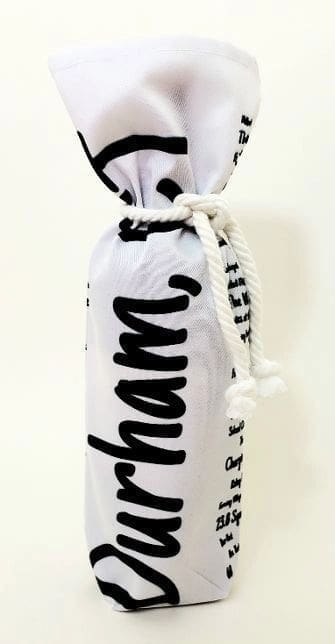 A bottle of wine in a bag with the word " charm " written on it.