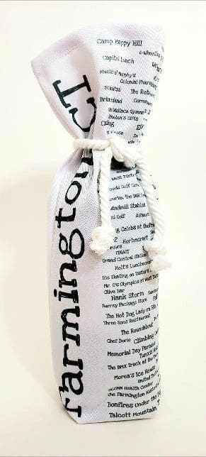 A bottle of wine wrapped in newspaper with rope.