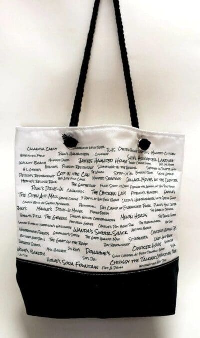 A white bag with black handles and writing on it.