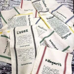 A pile of tea towels with different colored writing on them.