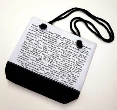 A white bag with black handles and writing on it.